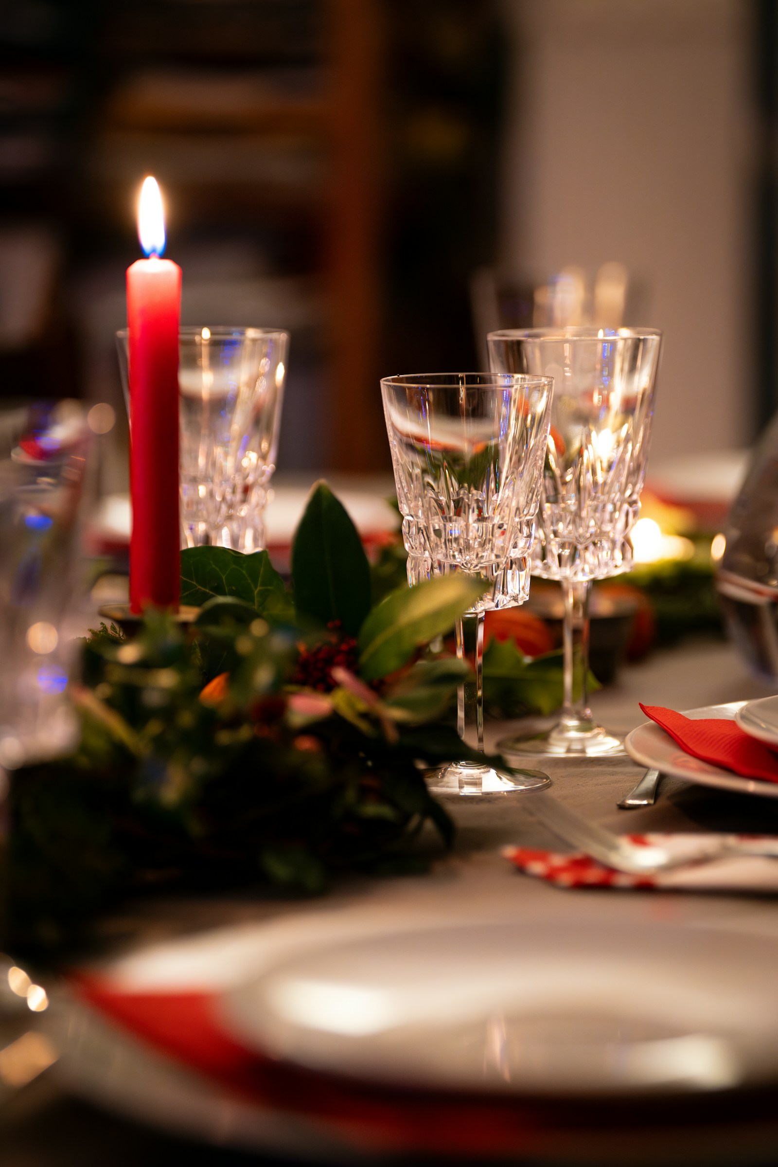 Holiday place setting with glassware, greenery and a candle